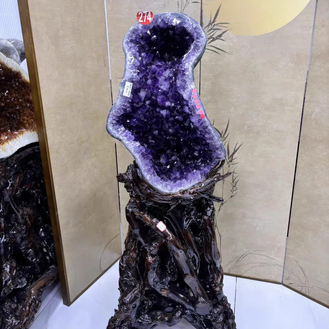 紫水晶洞立于金色屏风与竹影背景前